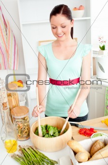 Glowing young woman preparing salad at home