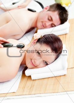 Charming young couple receiving a back massage with hot stones