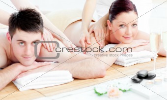 Merry young couple enjoying a back massage lying on a table massage with towels