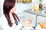 Positive businesswoman using her laptop during breakfast