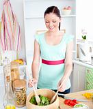 Delighted young woman preparing salad at home