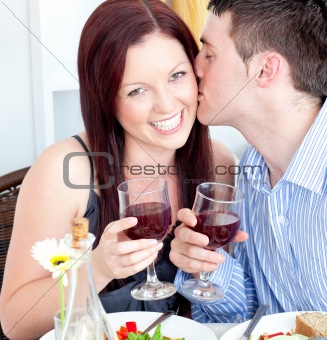 Happy boyfriend kissing his beautiful girlfriend during dinner