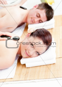 Lovely young couple receiving a back massage with hot stones