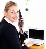 Happy young businesswoman talking on phone looking at the camera