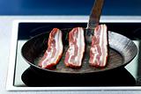 three stripes of bacon in a pan