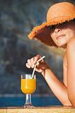 Attractive woman in hat with glass of orange juice