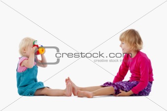 sisters taking pictures of each other with toy camera - isolated on white
