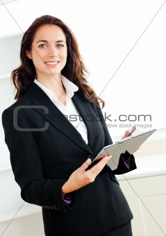 Glowing young businesswoman taking notes on her clipboard