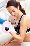 Musclar woman holding a dumbbell in her living-room