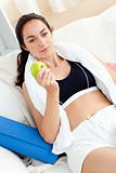 Young woman eating an apple on the sofa after working