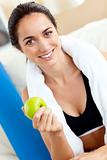 Radiant woman with apple and towel after exercising
