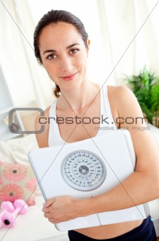 Portrait of a beautiful woman holding a scale in her living-room