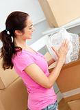 Joyful young woman unpacking boxes with glasses