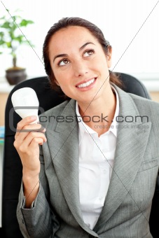 Thoughtful businesswoman holding a light bulb in her hand sittin