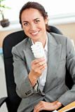 Attractive businesswoman holding a light bulb sitting in her off