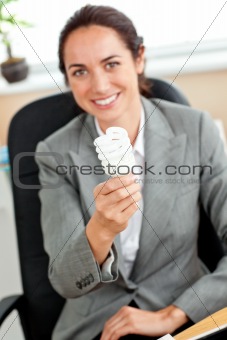 Attractive businesswoman holding a light bulb sitting in her off