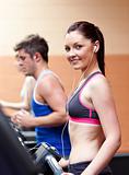 Cute athletic woman standing on a treadmill with earphones