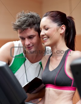 Cheerful athletic woman standing on a running machine with her p
