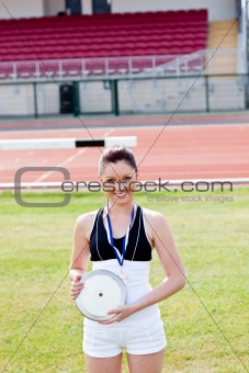 Smiling female athlete with a gold medal holding a disc