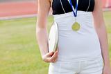 Close-up of a female athlete with a gold medal holding a disc
