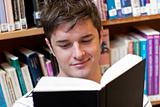 Portrait of a smiling male student reading a book sitting on the
