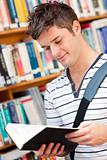 Cute male student reading a book