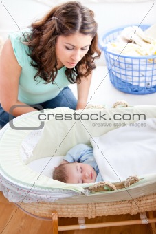 Young mother looking at her little son sleeping in his bed