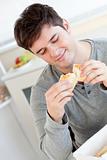 Delighted man eating bread in the kitchen