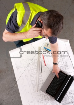Builder phones about construction blueprint