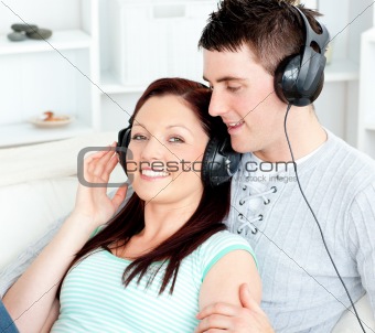 Charming couple listening to music with headphones lying on the 