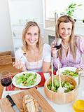 Pretty women eating a salad and drinking wine in the kitchen