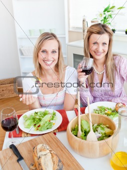 Pretty women eating a salad and drinking wine in the kitchen