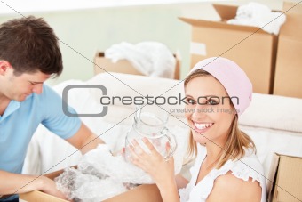 Delighted young couple unpacking boxes with glasses