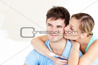 Hugging caucasian couple painting a room