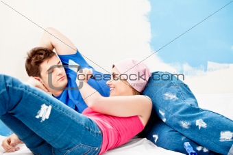 Young caucasian couple relaxing after painting a room