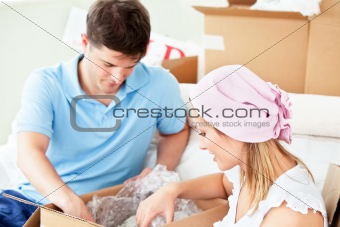 Serious caucasian couple unpacking boxes with glasses