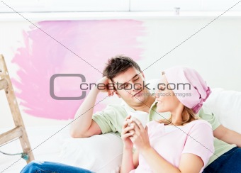 Resting caucasian couple lying on a sofa after painting a room