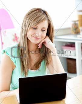 Kind caucasian woman using her laptop sitting in the kitchen