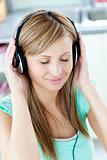 Young woman listening to music with headphones in the kitchen
