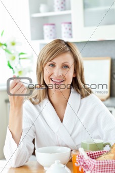 Cute woman having breakfast in the kitchen
