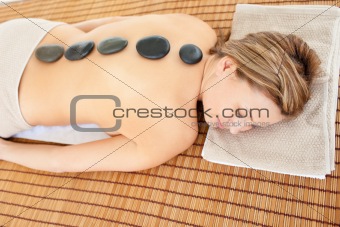 Resting caucasian woman lying on a massage table with hot stones