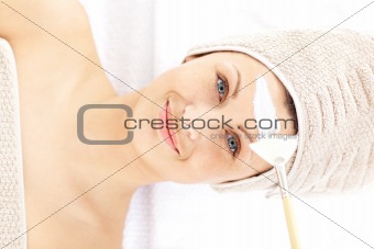 Happy woman receiving white cream on her face