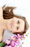 Beautiful woman lying on a massage table with flowers 