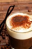coffee with milk froth, cocoa powder and standing vanilla beans