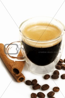 espresso in a glass cup with cinnamon and beans