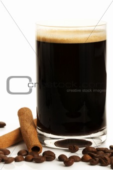 espresso in a glass with coffee beans and cinnamon sticks