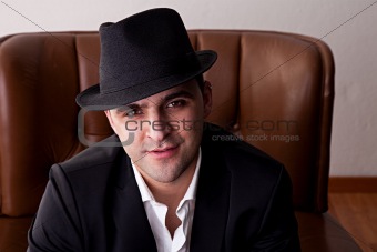 Man with hat seated on a chair