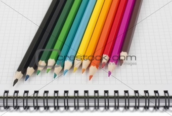 Multicolored pencils on spiral notebook