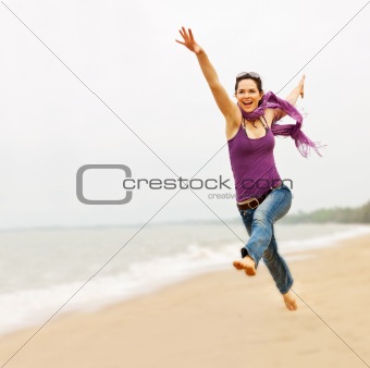 Beautiful young woman taking a great leap on the beach