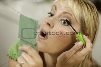 Blonde Woman Applying Her Mascara Makeup in Her Bathroom.